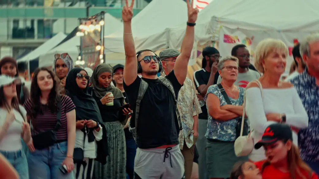 Festival-goers cheer with hands in the air beside the vendor tents