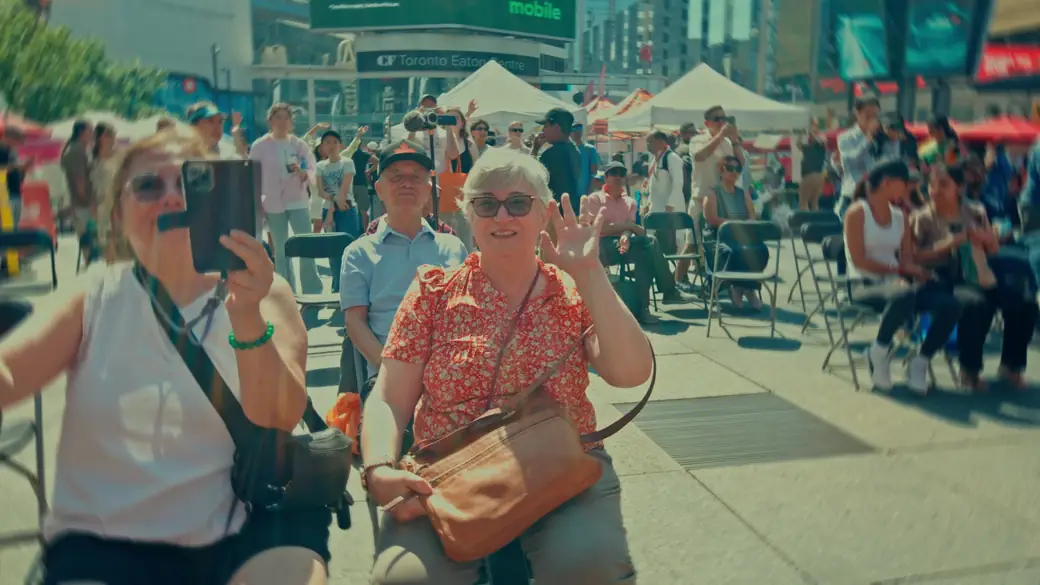 Two festival-goers smile and wave at the camera