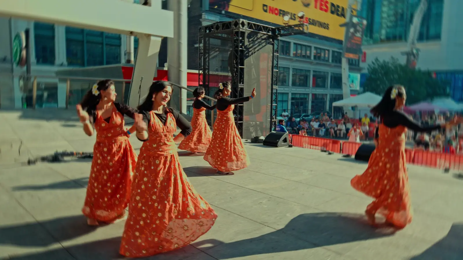Dancers in orange dresses perform on the WorldFest main stage at Yonge-Dundas
