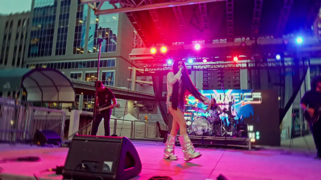 A band performs under pink and blue stage lights at night
