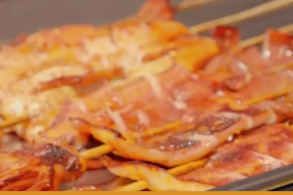 Grilled squid skewers on a tray at a WorldFest food stall